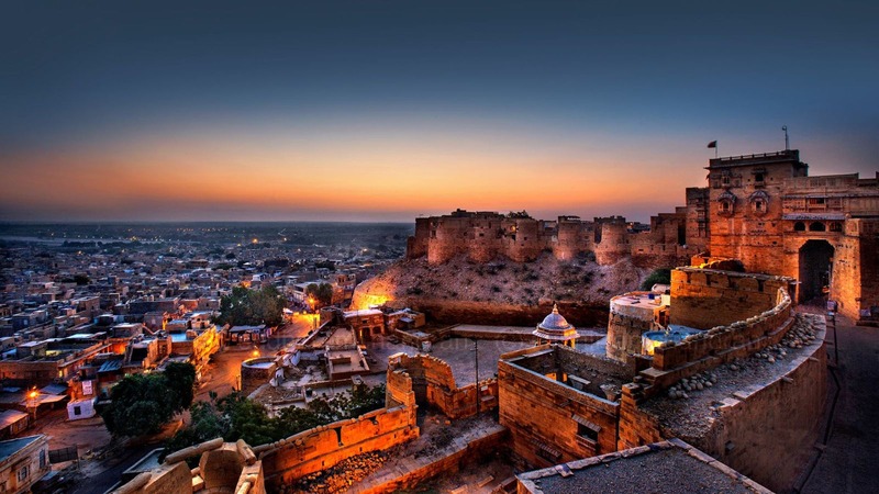 Jaisalmer Fort at sunset overlooking the Golden City, with illuminated sandstone walls and the Thar Desert skyline visit with raj tempo travelers.
